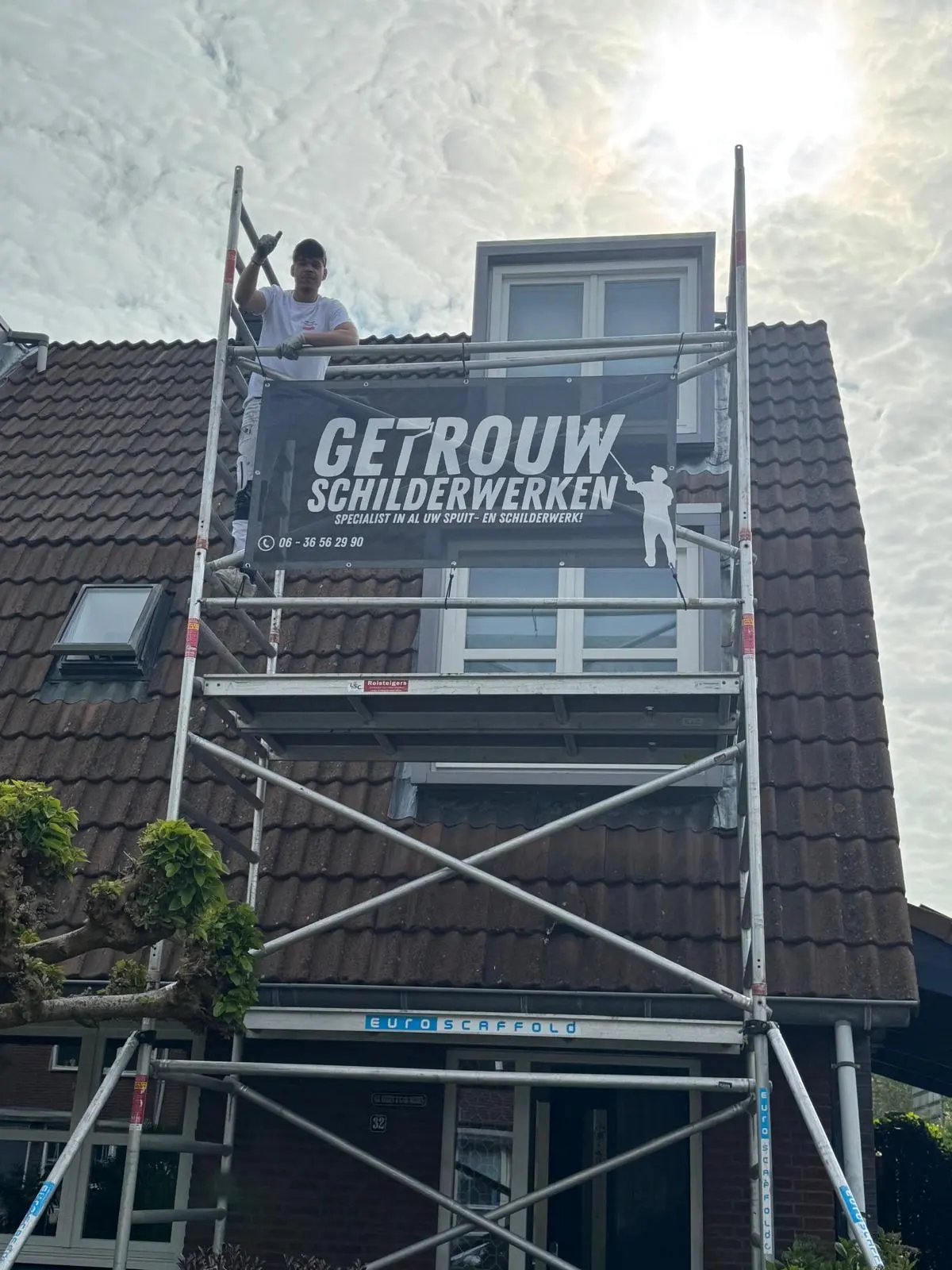 Steiger met spandoek bij een dakkapel